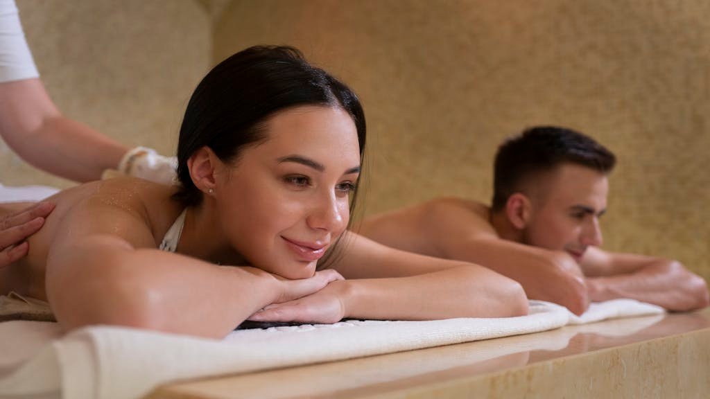 Couple receives relaxing massage treatment in serene spa setting.